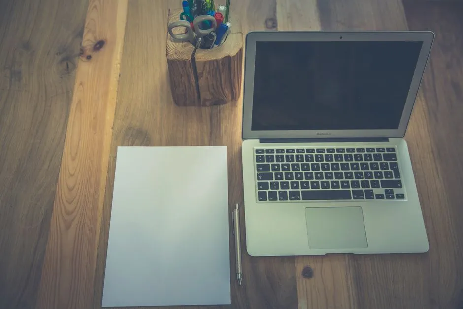A laptop and paperwork on a wooden desk