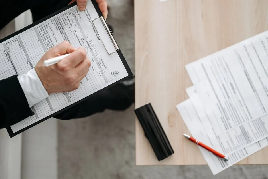 A hand holding a clipboard while filling out a form